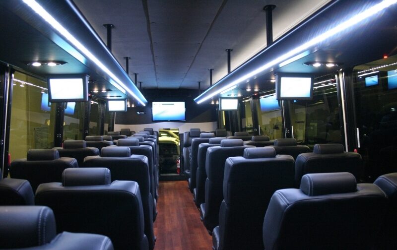 A bus with many seats and two tvs on the side.