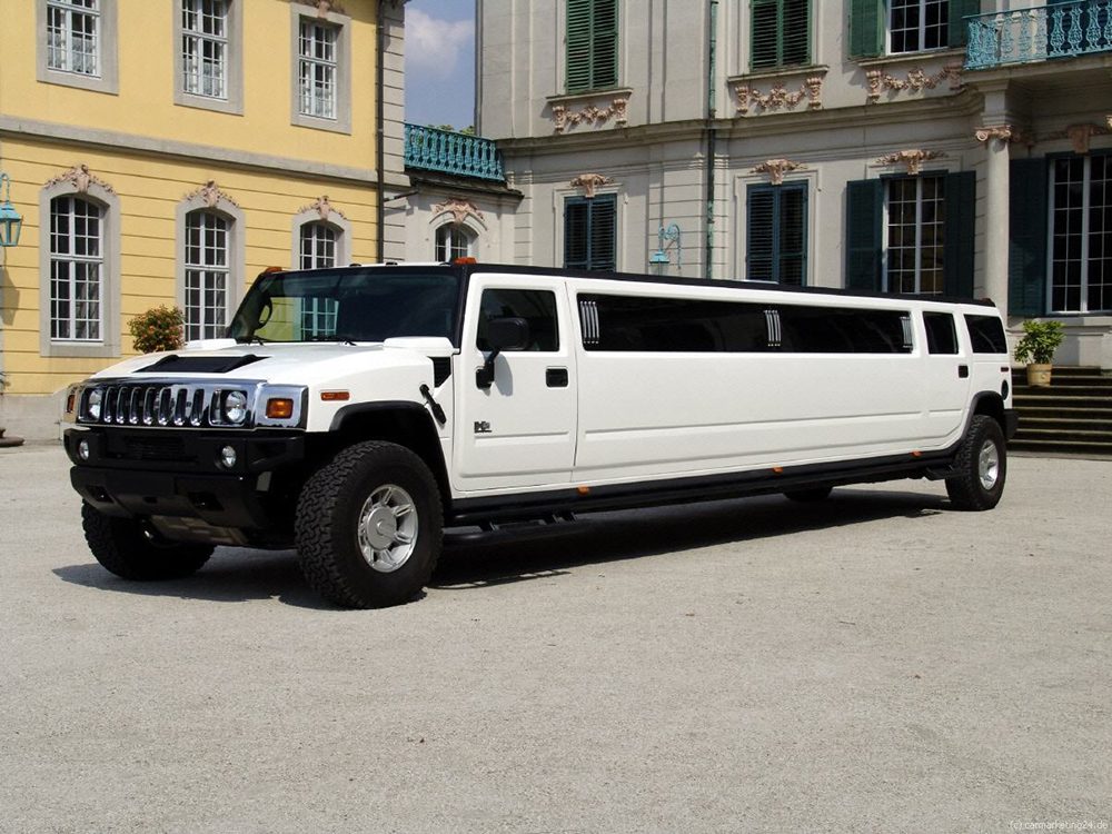 A white hummer limo parked in front of some buildings.