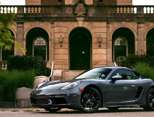 A grey car parked in front of a building.