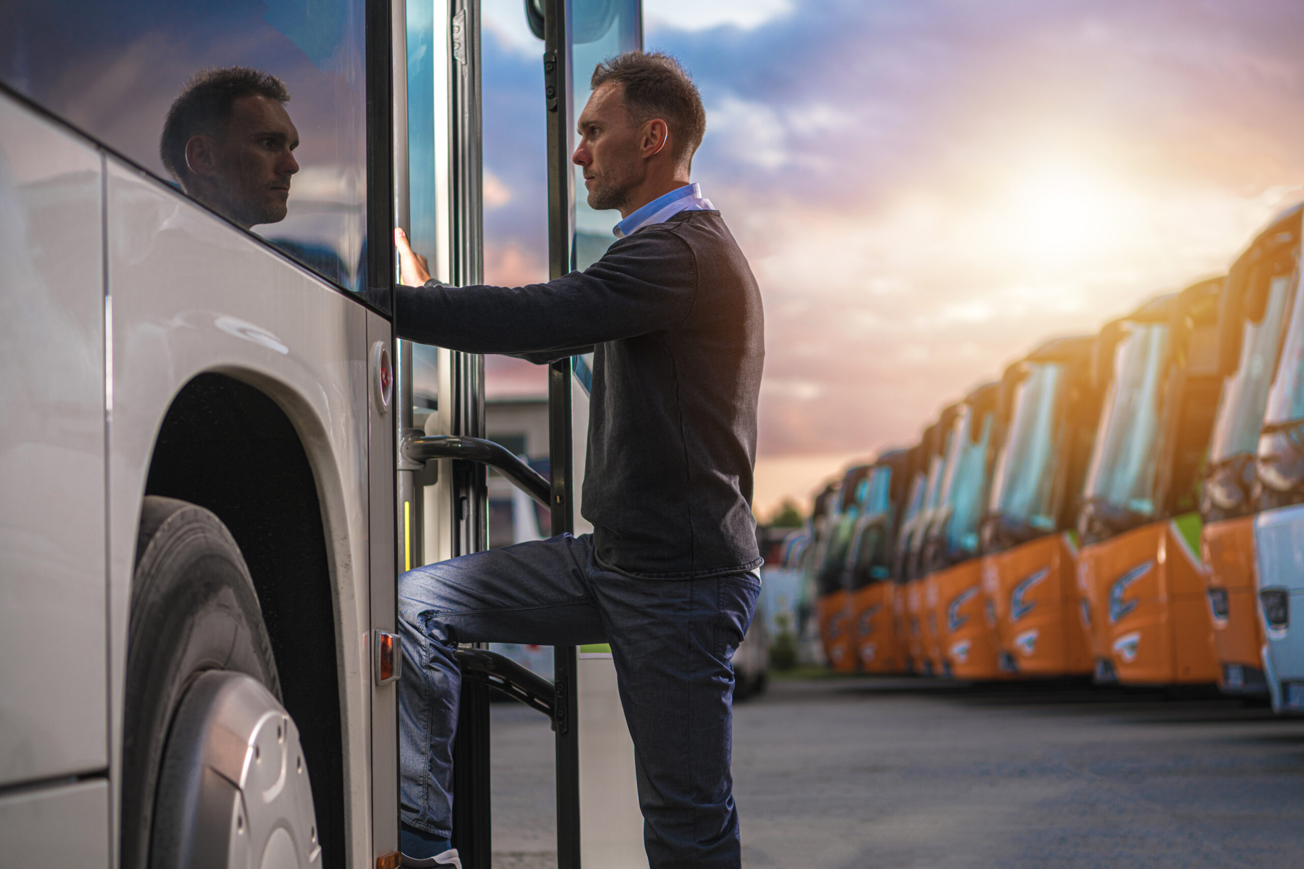 A man standing next to a bus on the side of the road.