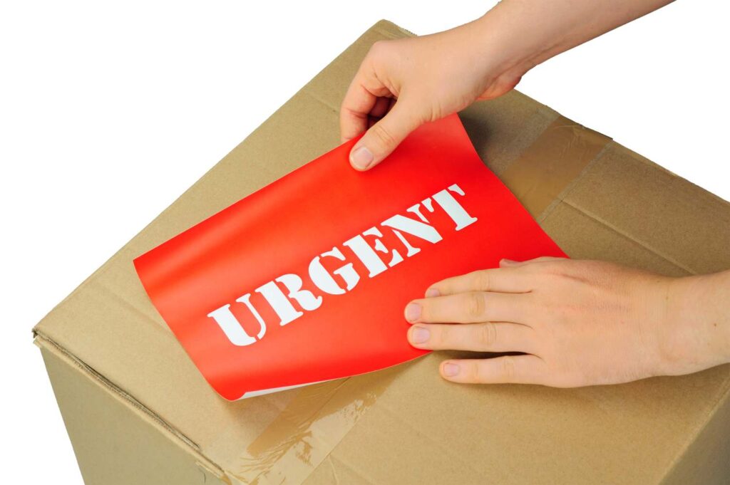 A person is putting the word urgent on a cardboard box.