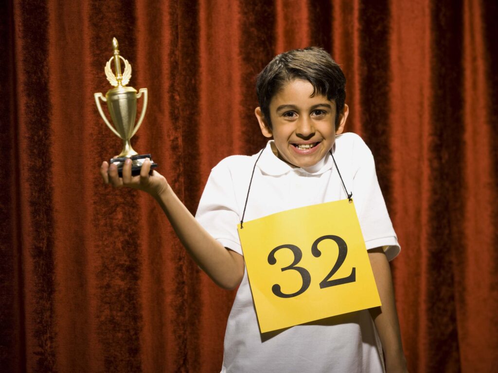 A young boy holding a trophy and wearing an apron.