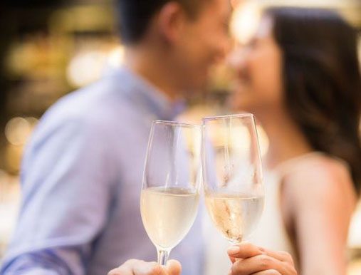 A man and woman holding wine glasses in front of each other.