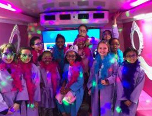 A group of girls in costumes on the back of a bus.