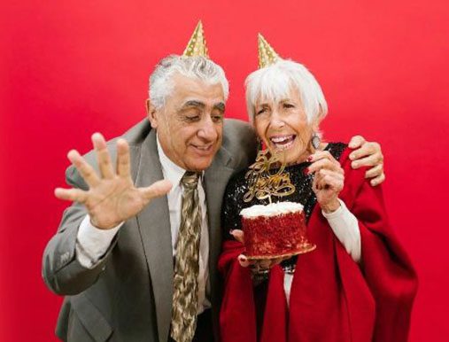 A man and woman wearing party hats with cake.