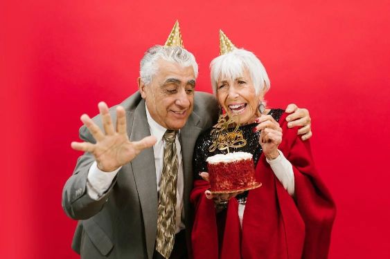 A man and woman wearing party hats next to a cake.