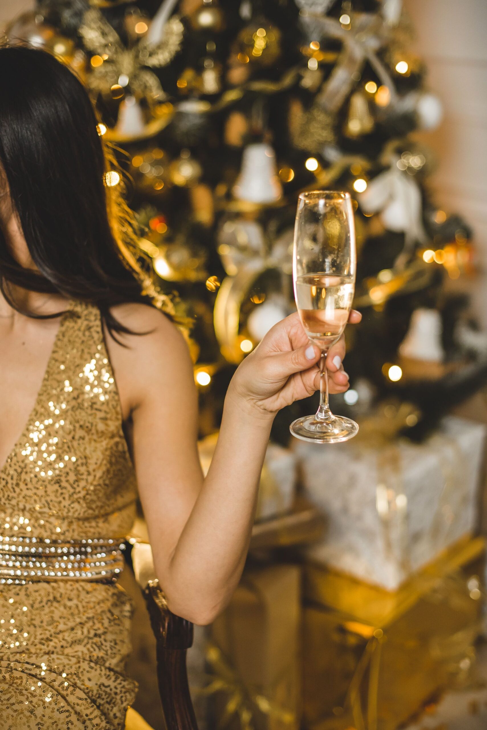 A woman in gold dress holding up a glass of champagne.