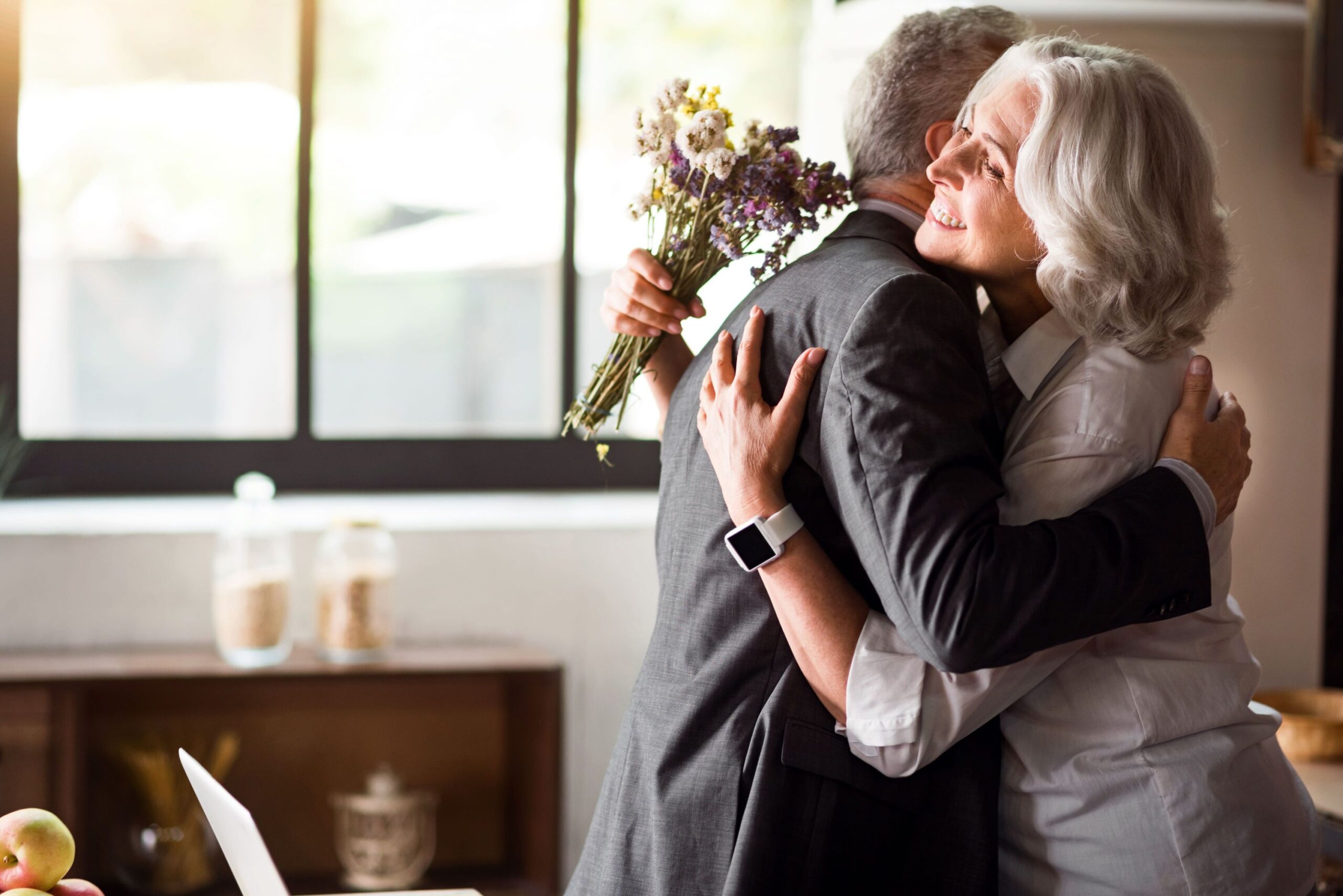 A man and woman kissing each other while holding flowers.