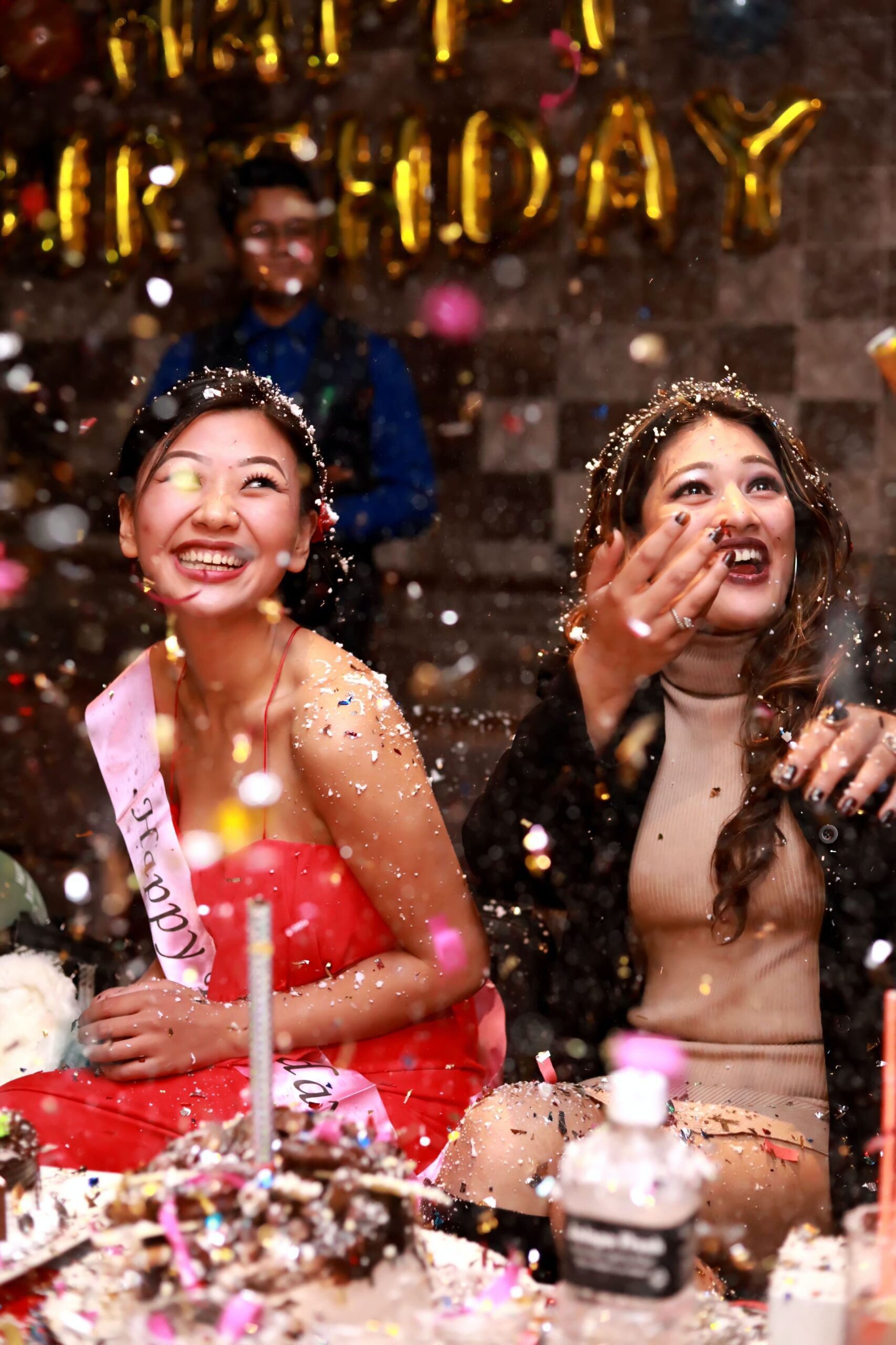 Two women are celebrating with confetti and candles.