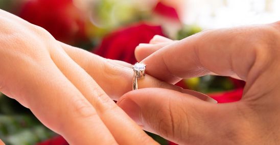 A person is holding their wedding ring in her hand.