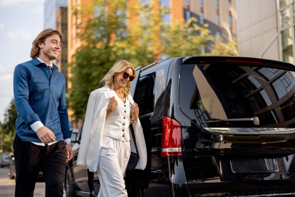Man and woman walking toward black vehicle.