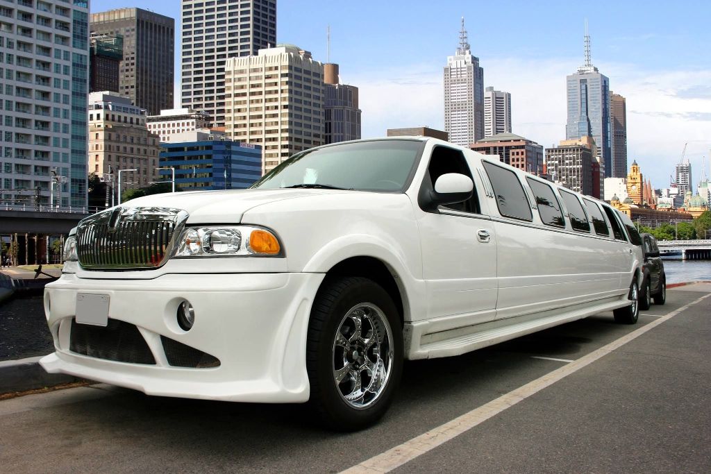 A white stretch limousine parked on a city street below the skyline