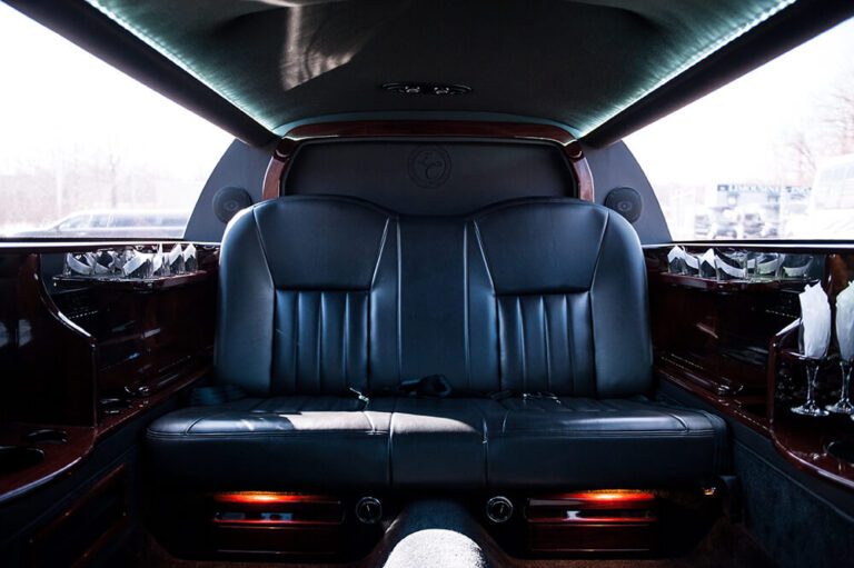 Interior of a Lincoln limousine showing black leather bench seating and wood trim